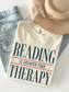 ivory comfort colors reading is cheaper than therapy shirt flat lay styled with denim jeans and beige hat aesthetic