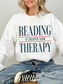 white oversized sweatshirt featuring reading is cheaper than therapy quote for readers bookworms and cozy reading aesthetic