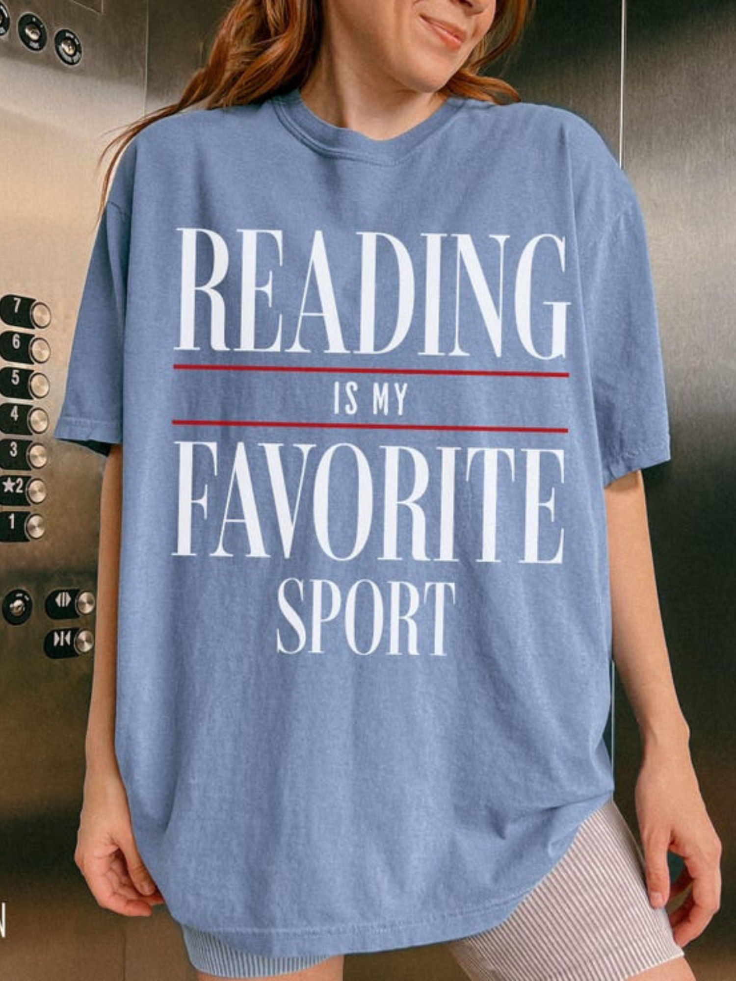 woman wearing blue jean reading is my favorite sport comfort colors t shirt posing in elevator with casual oversized book lover outfit