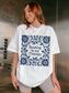 A woman wearing an oversized white t-shirt with a navy blue floral border and the text 'Reading is my Therapy' printed on the front, standing in a metallic elevator lobby.