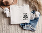 folded white sweatshirt with cute raccoon holding a book and funny reading trash text on front