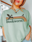 woman wearing bay comfort colors bookworm shirt featuring vintage rainbow stripes and dragon silhouette fantasy reader graphic