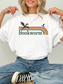 woman wearing white comfort colors fantasy bookworm shirt with retro rainbow stripes dragon silhouettes and cozy reader design