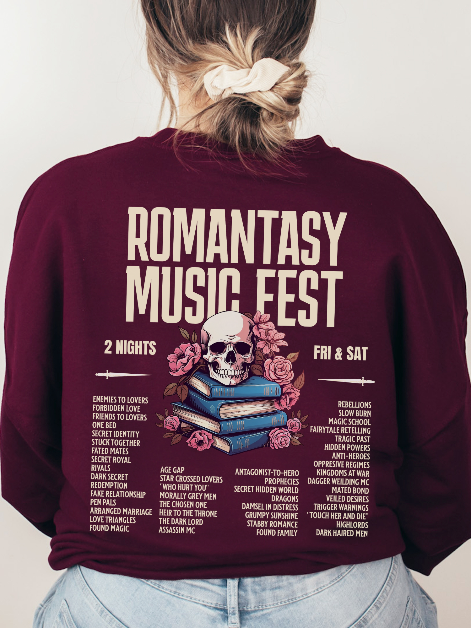 Maroon crewneck sweatshirt shown from the back with large Romantasy Music Fest print, showcasing a fantasy-inspired concert-style design with a skull, flowers, and popular romantasy tropes.