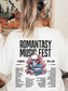 White sweatshirt with Romantasy Music Fest graphic on the back, including a pink floral skull atop books and fantasy tropes like morally grey men and found magic, modeled with loose waves in a cozy indoor setting.