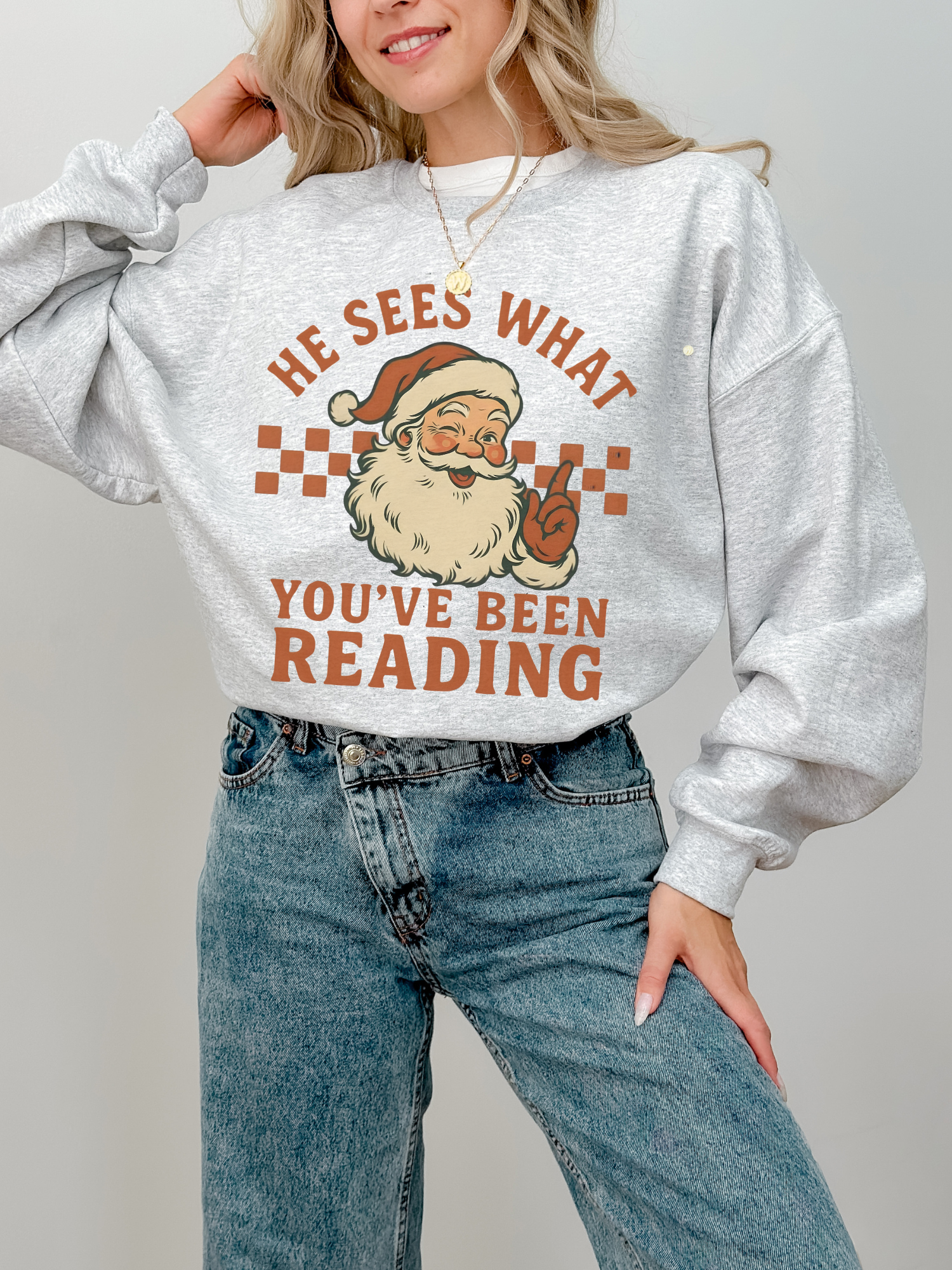 girl wearing ash grey sweatshirt with santa graphic and spicy bookish saying