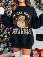 woman in black sweatshirt standing in front of Christmas tree holding Santa mug, festive background