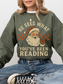 girl wearing military green sweatshirt with santa graphic and the words he sees what you've been reading