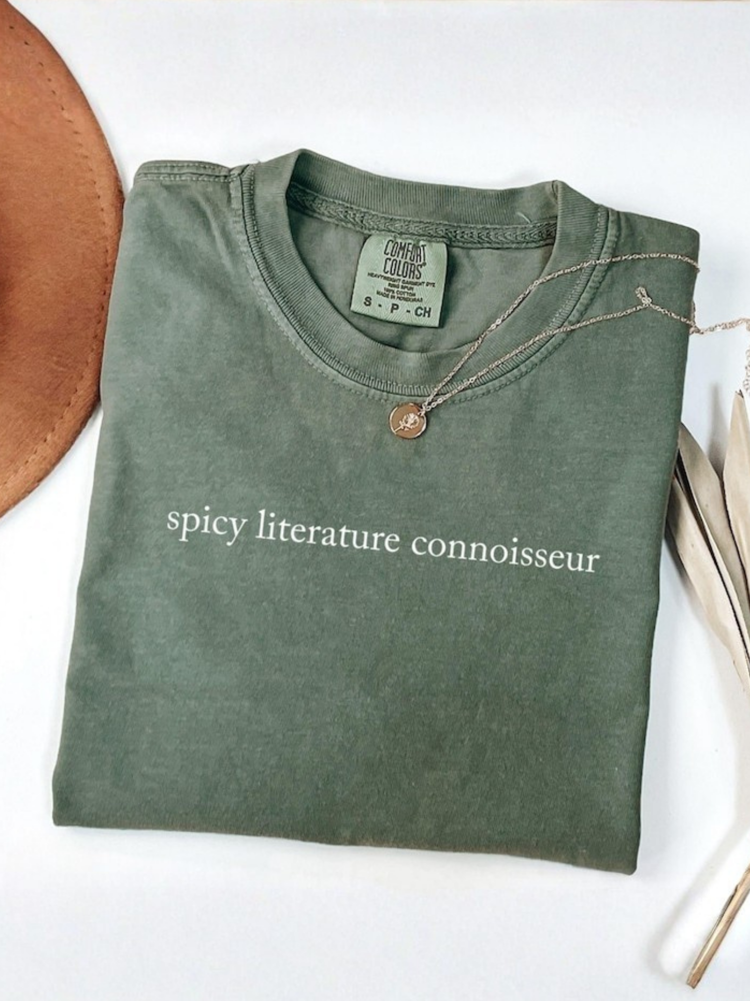 folded moss green Comfort Colors t-shirt with spicy literature connoisseur quote and bookish styling