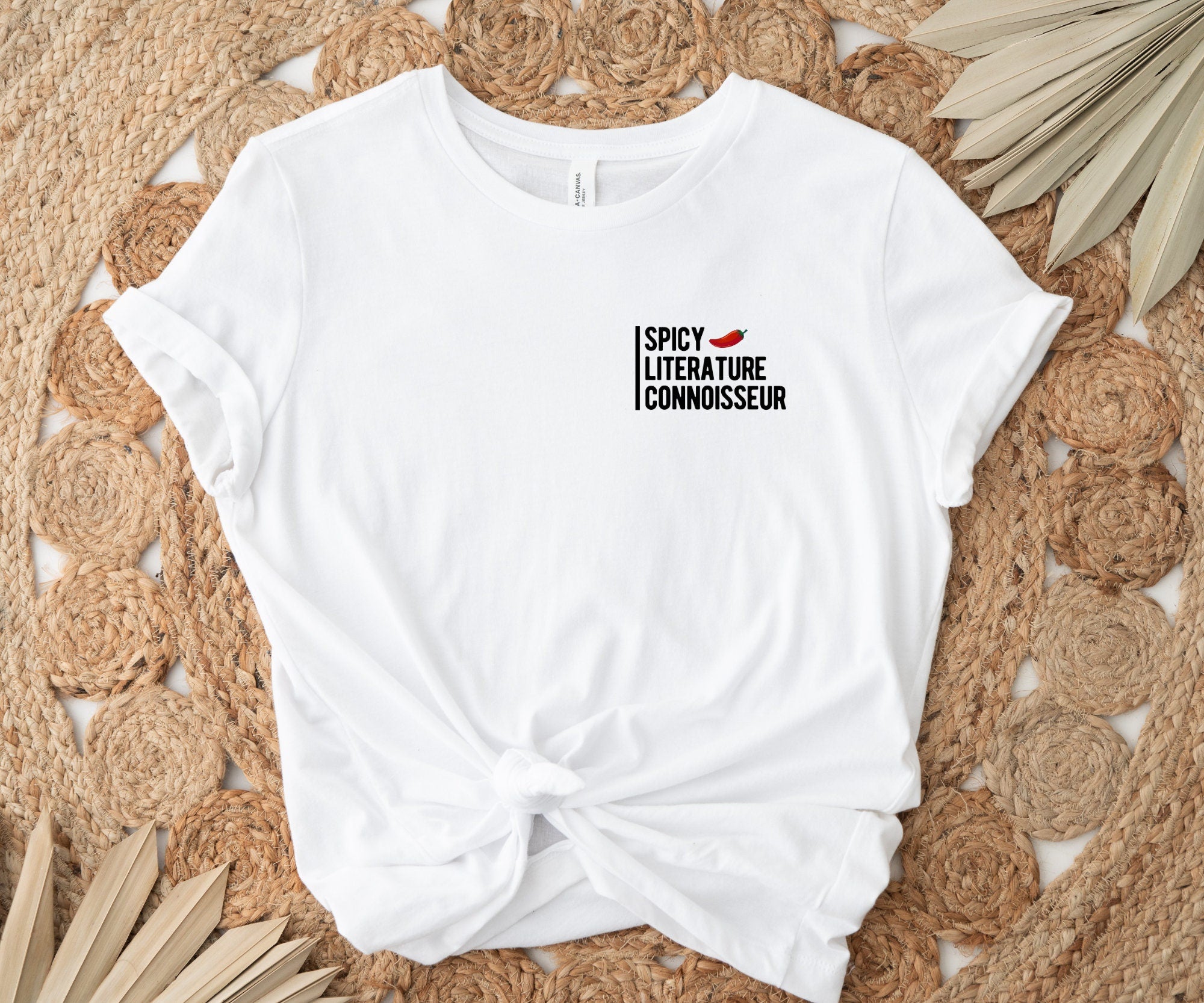 white t-shirt tied at the waist with spicy literature connoisseur design laid on woven boho rug