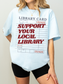 woman wearing light blue oversized support your local library t shirt with vintage library card graphic and casual outfit styling