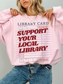 woman wearing pink sweatshirt with support your local library graphic and vintage library card design styled in cozy casual outfit