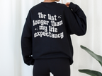 woman wearing oversized black sweatshirt with bold white bookish quote about a long TBR list