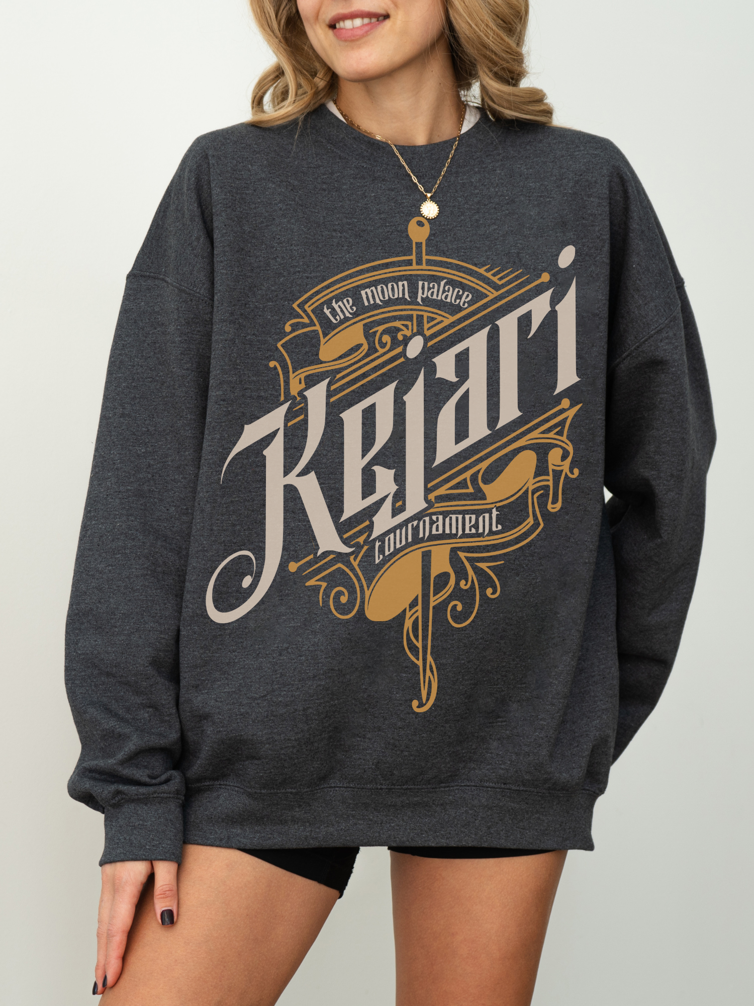 Dark heather grey crewneck with intricate sword and scroll design from The Moon Palace, styled simply for cozy reading days or book club outfits.