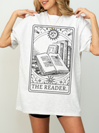 Woman wearing The Reader book tarot shirt in ash grey, styled with biker shorts for a comfy bookish look
