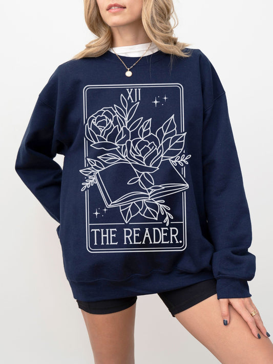 woman in navy The Reader tarot sweatshirt with bold white mystical floral book print