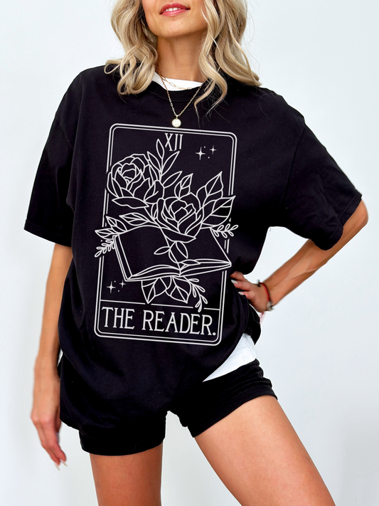 woman in oversized black t-shirt with bold mystical book and floral design labeled The Reader