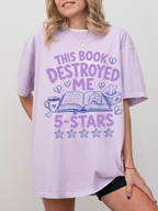 woman wearing lavender oversized t shirt with this book destroyed me 5 stars design featuring book review inspired graphics and purple lettering