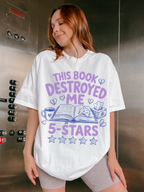 woman wearing white oversized t shirt with this book destroyed me 5 stars design featuring open book coffee cup tissue box and heart illustrations