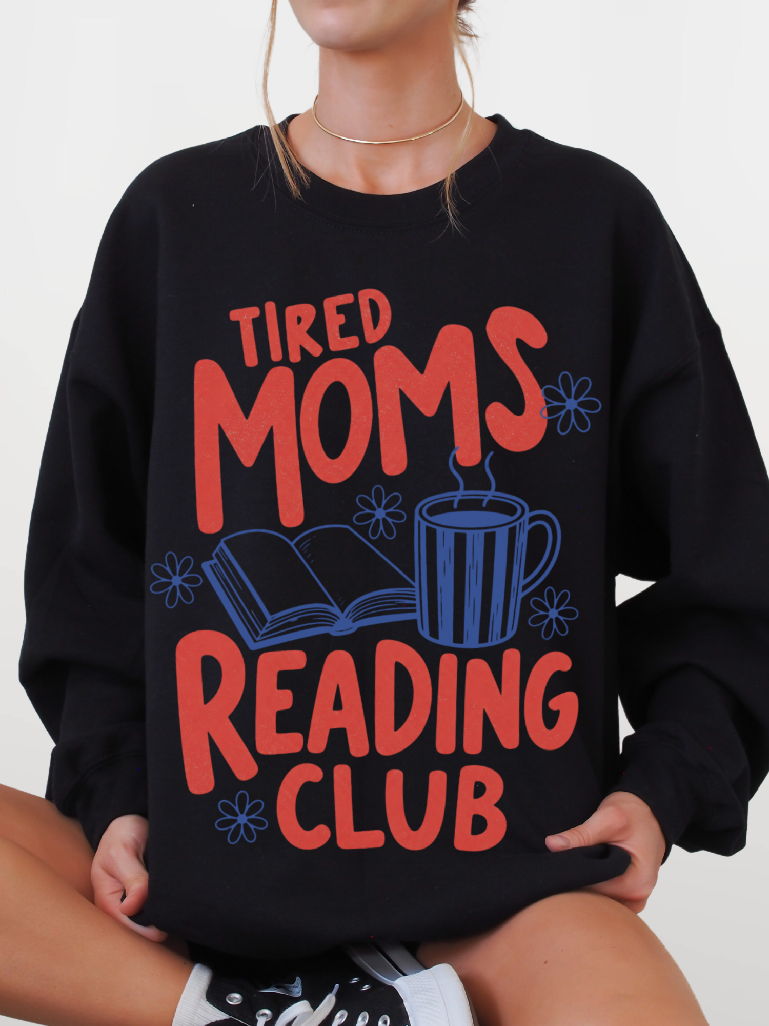 woman wearing black tired moms reading club sweatshirt with retro book lover design featuring coffee cup open book and flowers