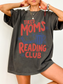 woman wearing oversized pepper comfort colors tired moms reading club t shirt with vintage reading graphic coffee cup and flowers