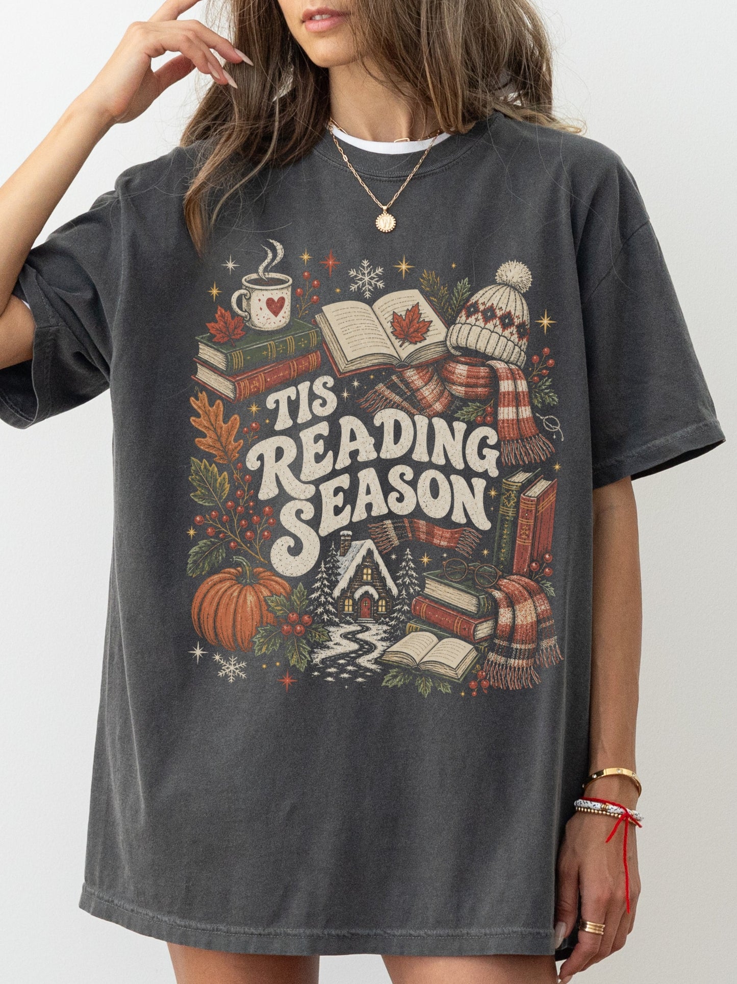 Pepper Comfort Colors shirt modeled with a vintage Tis Reading Season design featuring books, coffee mug, pumpkin, fall leaves, scarf, winter hat and snowy cottage, bookish shirt for avid readers