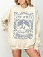 woman wearing a sand-colored sweatshirt with Velaris crest and City of Starlight text in blue grey ink