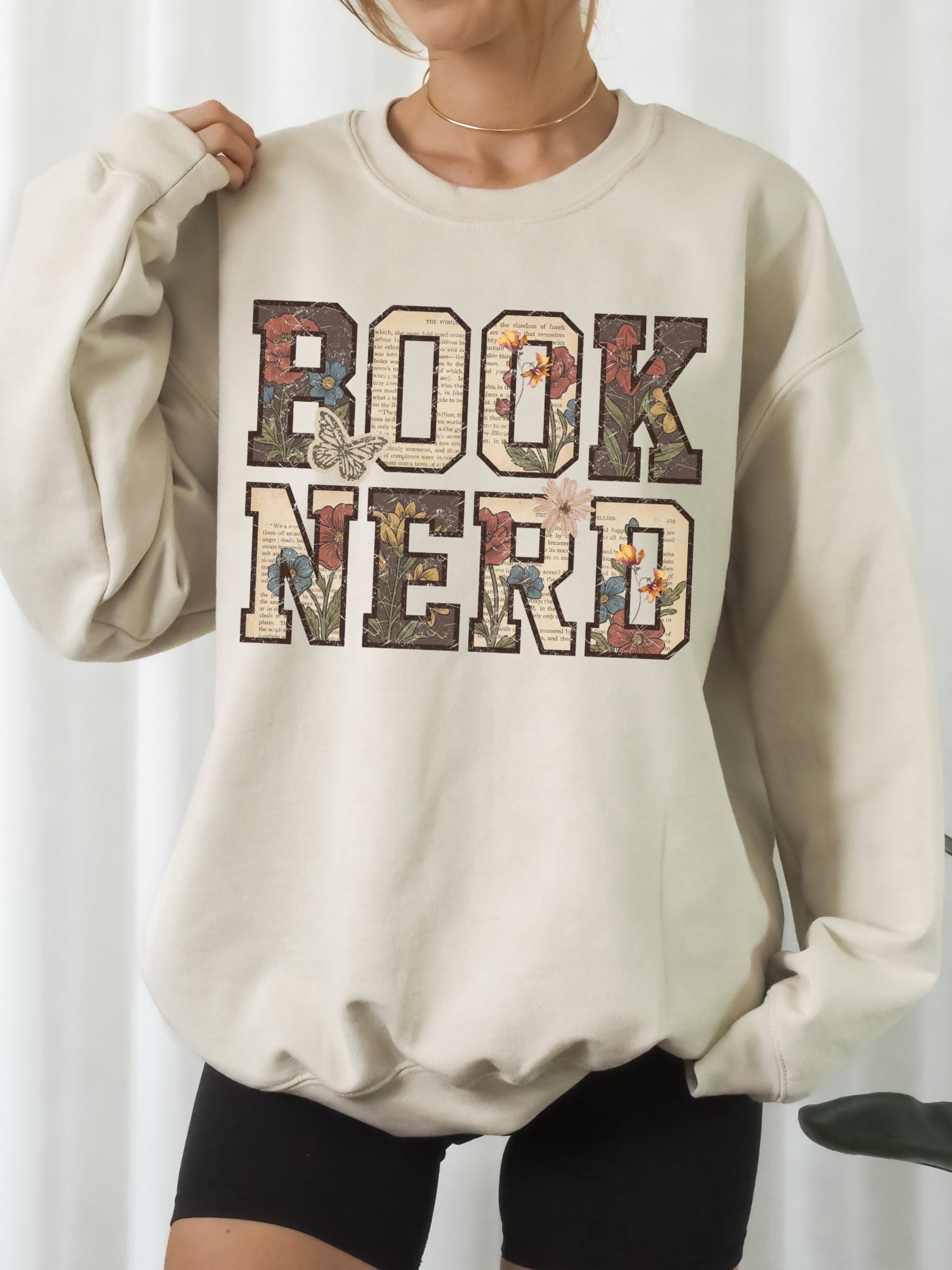 Sand Gildan sweatshirt featuring a vintage Book Nerd design filled with book pages, wildflowers and butterflies, cozy book lover sweatshirt for avid readers