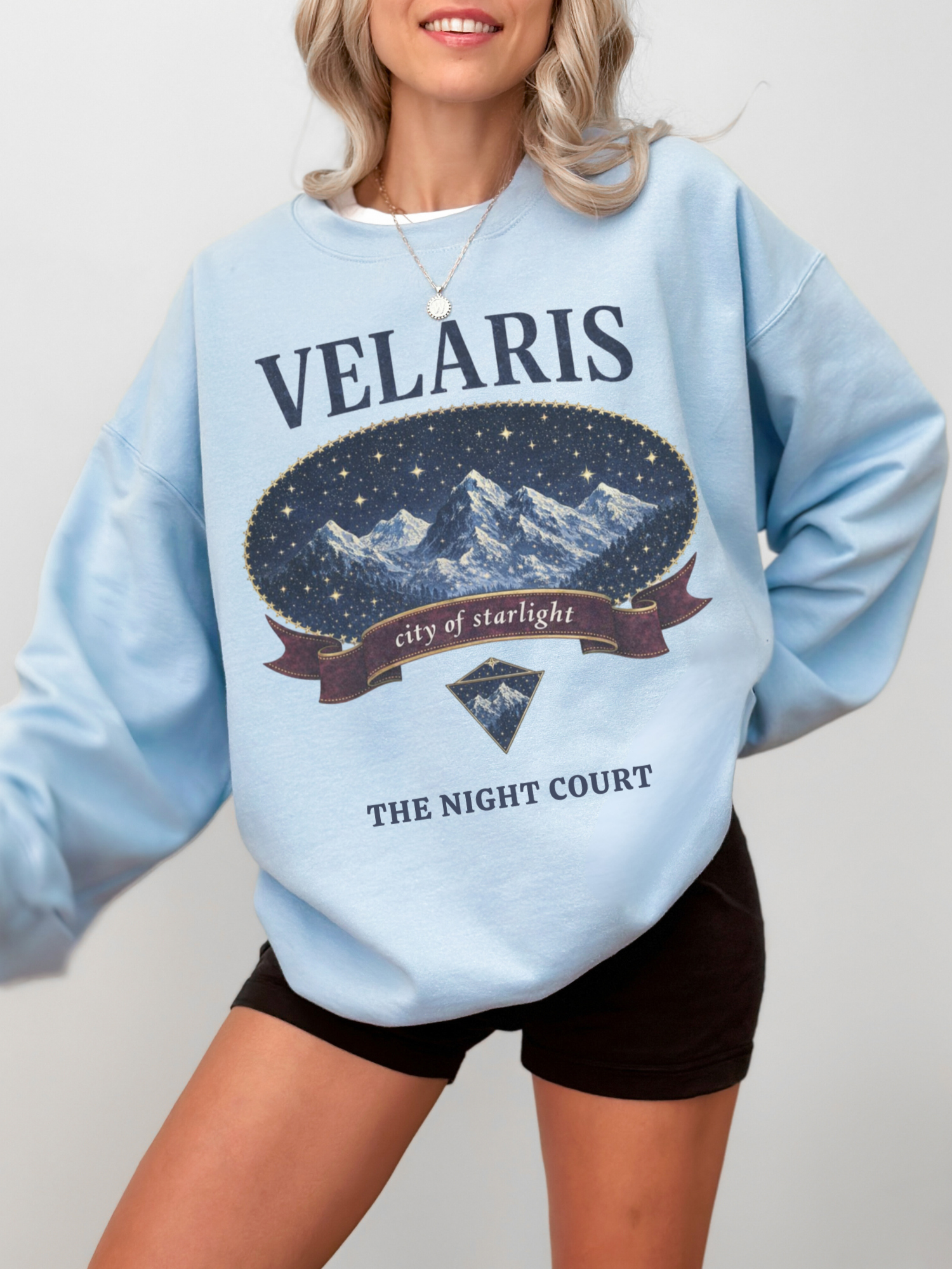 woman wearing a light blue vintage velaris sweatshirt with starry fantasy landscape graphic