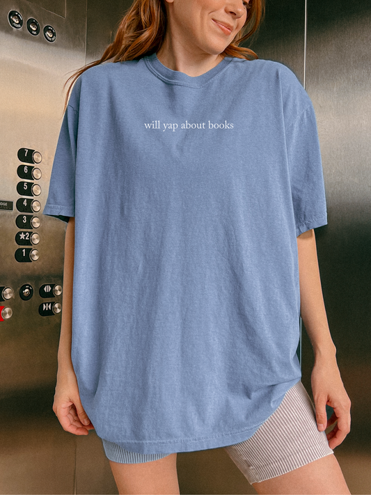 woman wearing a blue jean t-shirt in an elevator that says will yap about books in minimalist white text
