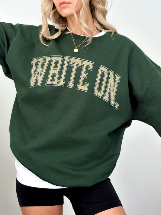 woman in forest green write on sweatshirt with golden vintage text, wearing necklace and black shorts